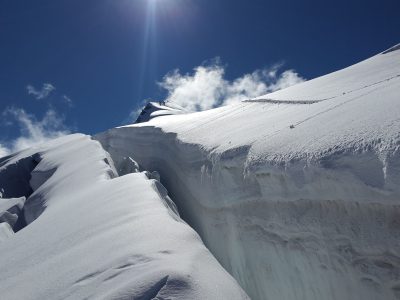 A breathtaking view of a pristine alpine glacier under a clear blue sky with the sun shining brightly.